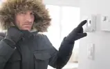 Мужчина в куртке включает котел